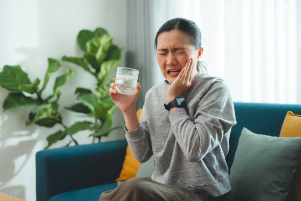 a woman experiencing tooth sensitivity after drinking cold water