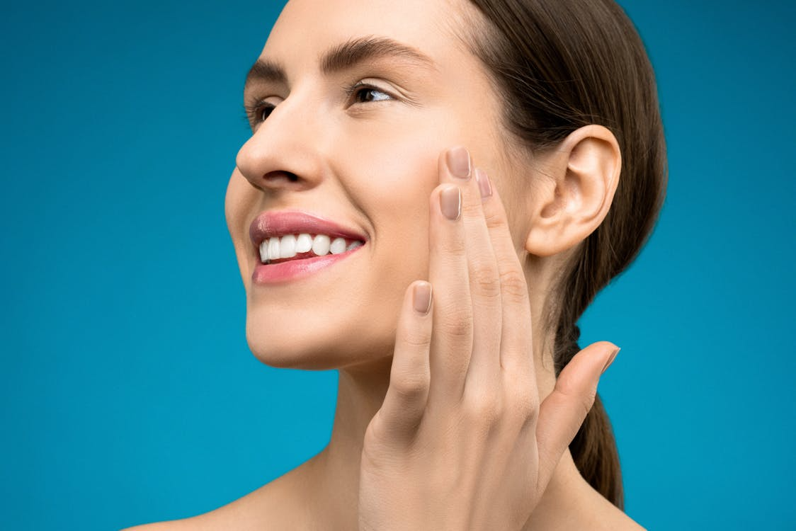 image of a woman smiling while touching her cheeks