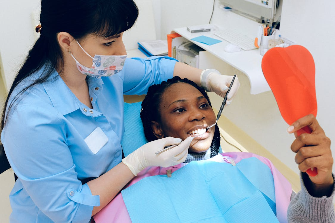 a dentist showing the patient her teeth through a handheld mirror