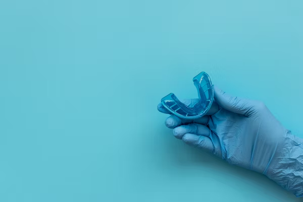 a hand with gloves holding a dental splint